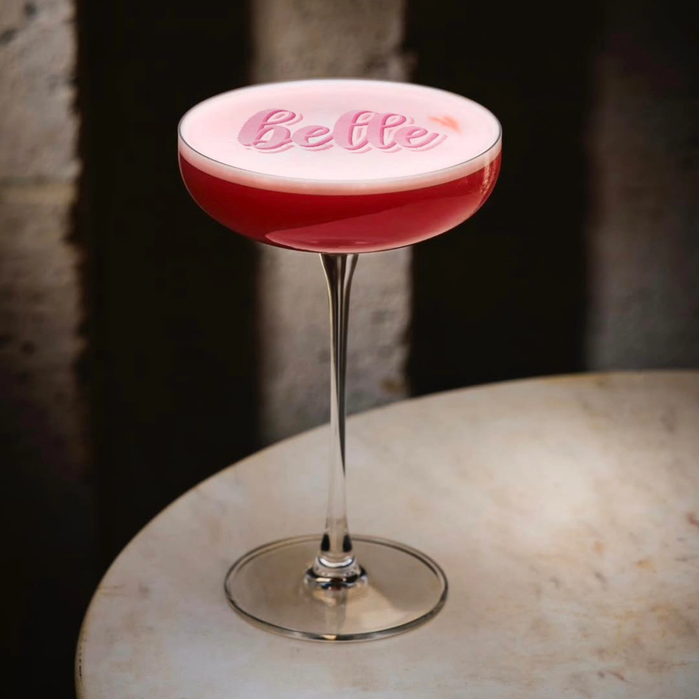 Cocktail-Drucker: 'Belle' Text auf rotem Cocktail-Schaum auf Glastisch