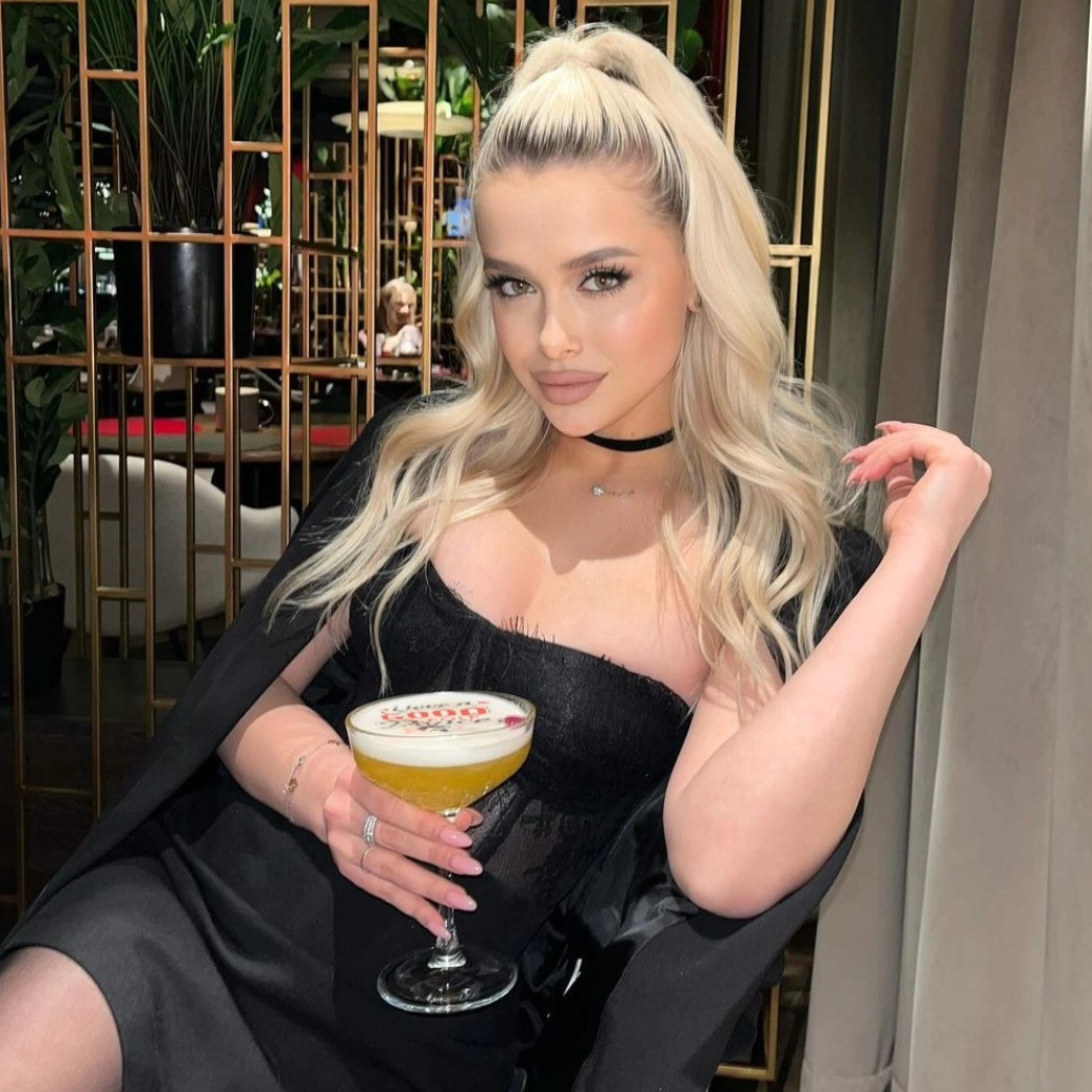 Frau hält Cocktail mit Logo auf dem Schaum aus einem Cocktail-Drucker, Hintergrund in einem Café