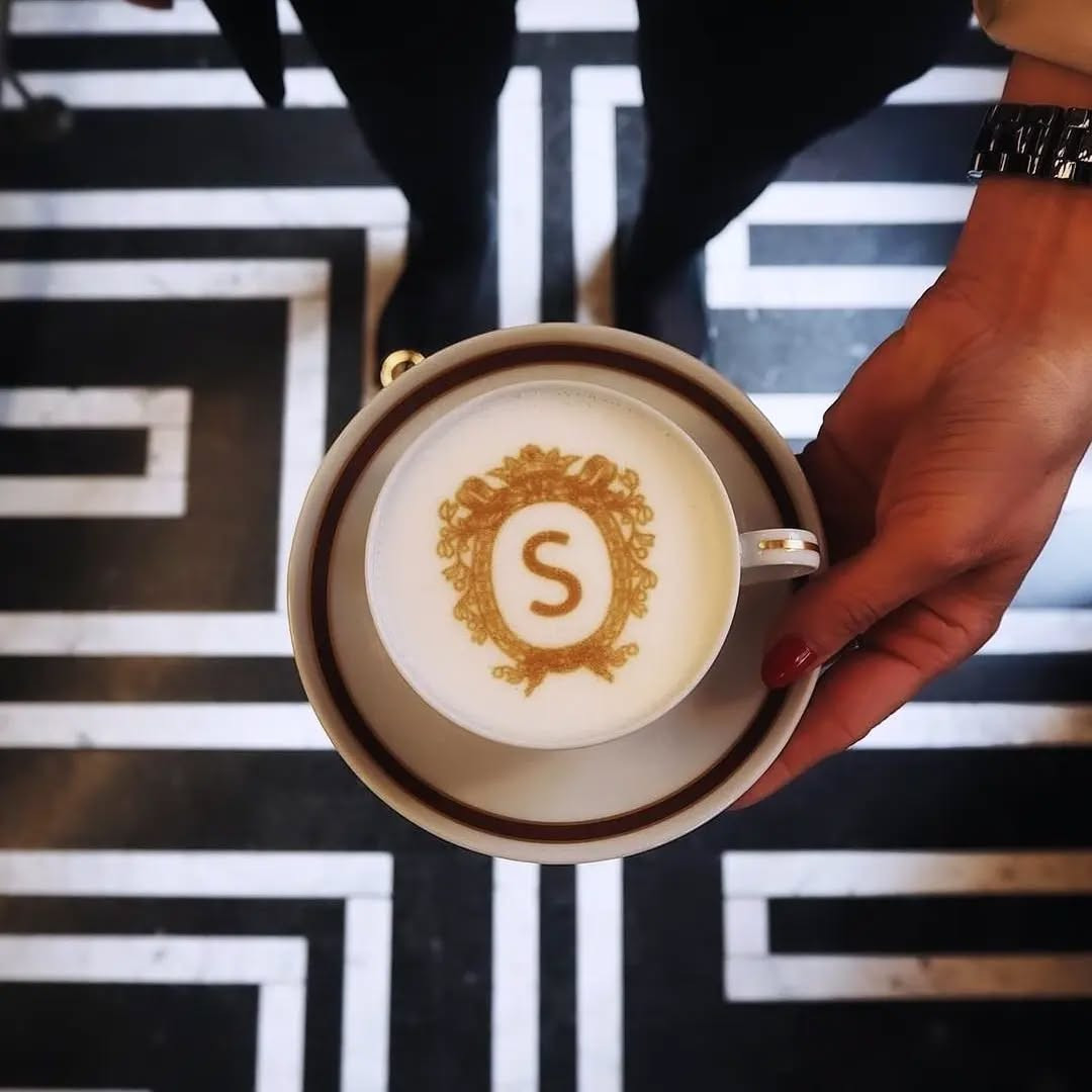 Drukarka latte art z monogramem 'S' na cappuccino w dłoni
