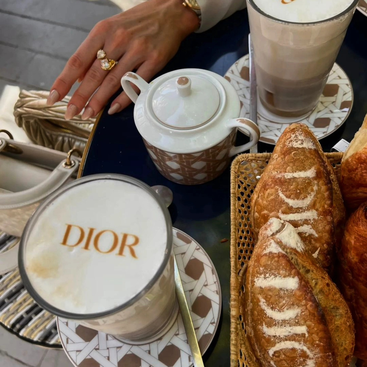 Impresora latte art: logo Dior sobre espuma de latte con croissants, junto a un bolso