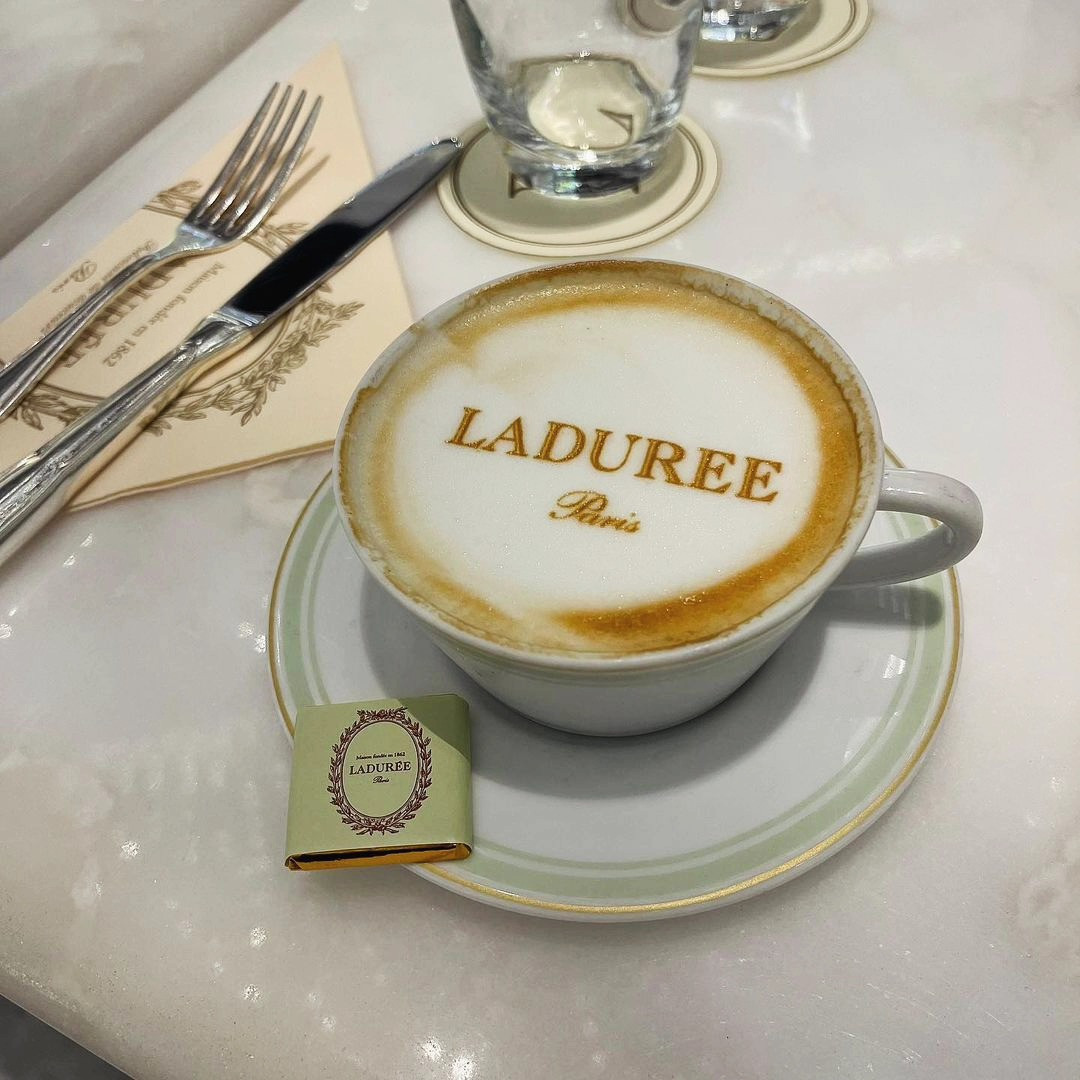Impressora latte art com logo Ladurée na espuma do cappuccino em um café elegante
