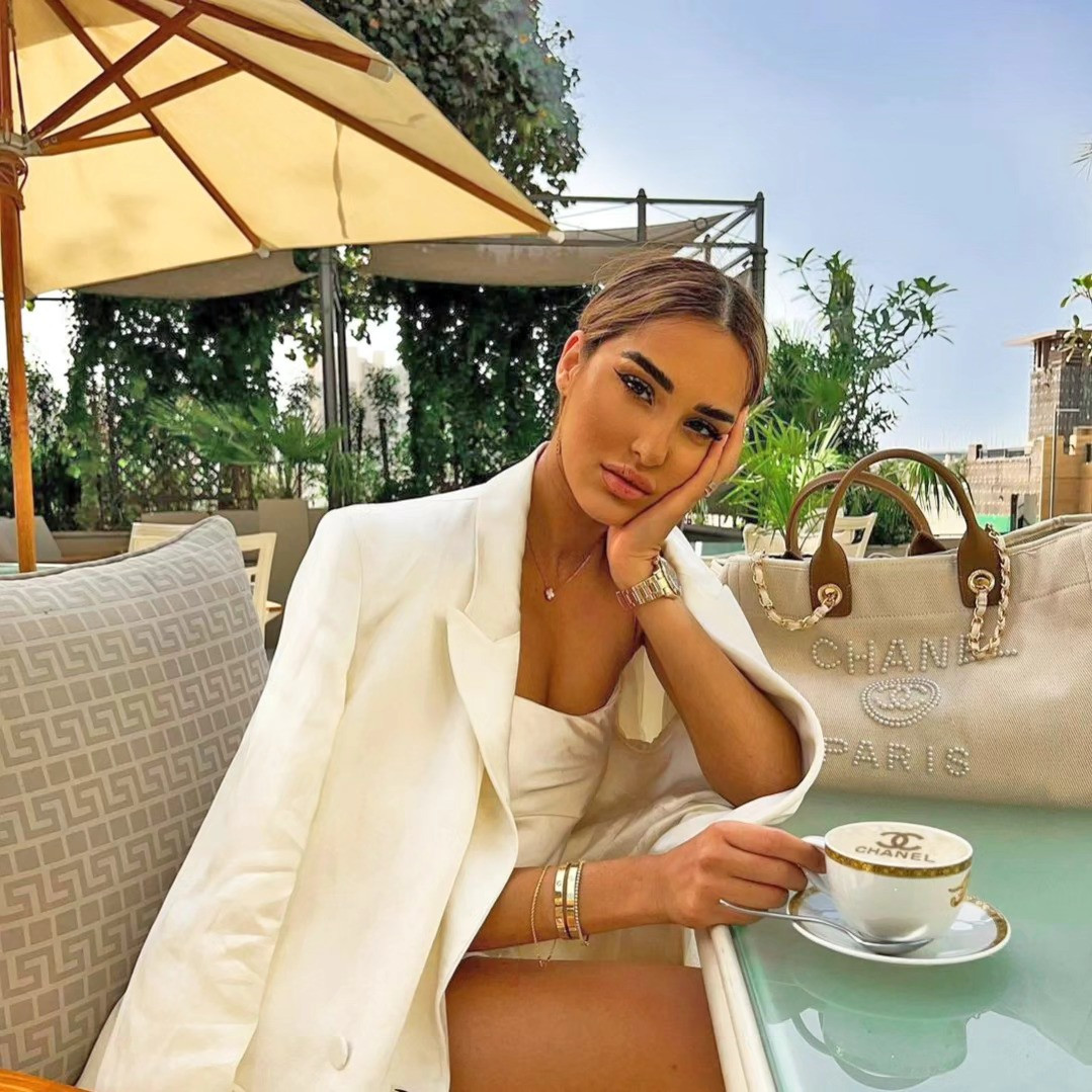 Frau mit Kaffee auf der Terrasse, Schaum mit Logo und Designertasche