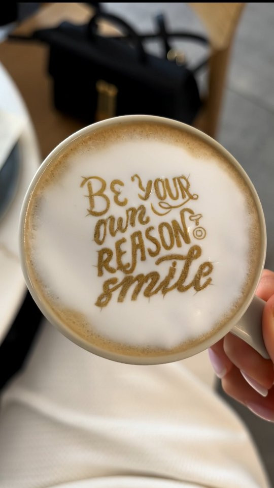 Milchschaumdrucker mit dem Text 'Be Your Own Reason To Smile' auf dem Schaum
